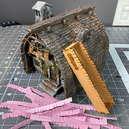 A fantasy house with shingles. There are foam cutouts beside it showing how the shingles are made